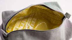 A silver hand-sewn Dopp kit bag with yellow waterproof lining fabric made in Ashley Nickel's Creativebug class.