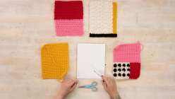 An overhead shot of a pair of hands over five crocheted swatches.