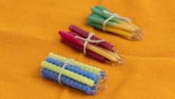 Three bundles of rolled and hand-dipped beeswax candles tied in white cotton twine.