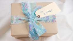Gift with tag reading Love, Mercedez, wrapped in brown paper and tied in a hand-marbled ribbon