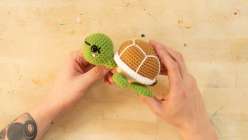 A pair of hands assembling a stuffed crocheted turtle from Vincent Green-Hite's Crochet an Amigurumi Turtle Creativebug class