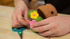 A pair of hands assembling a stuffed crocheted flower pot from Vincent Green-Hite's Crochet an Amigurumi Potted Cactus Creativebug class