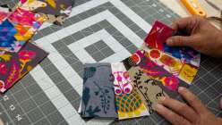A pair of hands holding a wedge of patchwork fabric from Sarah Bond's Creativebug Pickle Dish Quilt Block class