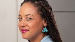 A woman with pink lipstick and locs wearing turquoise spotted clay earrings