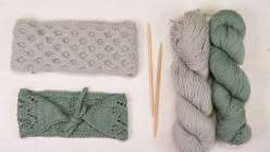 A grey cable knit headband, a green lace headband, and two skeins of yarn in grey and green from Faith Hale's Creativebug Knit Headbands Three Ways class.