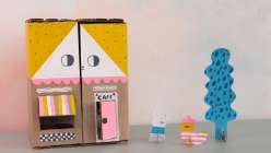 An image of a smiling doll house made out of cardboard from Suzy Williams's Sustainable Play: Make a Dollhouse Cafe class on Creativebug