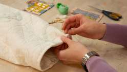 A pair of hands hand-sewing a laptop sleeve from Heidi Parkes's Sew a Quilted Laptop Slipcase class on Creativebug