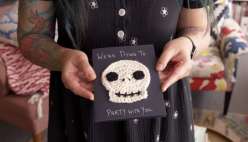 Hands holding a crocheted skull on a black piece of paper from Twinkie Chan's Crochet Halloween Appliques class on Creativebug