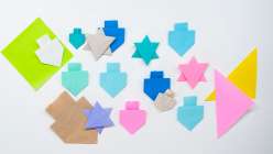 Paper dreidles and stars of David on a tabletop, made in Faith Hale's Hannukkah Origami class on Creativebug
