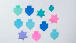 Paper dreidles and stars of David on a tabletop, made in Faith Hale's Hannukkah Origami class on Creativebug