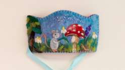 A felted kid's crown featuring the image of a mouse, clouds, and a mushroom made by Melissa Lyttle in her Wool Felting: Make a Woodland Celebration Crown class on Creativebug