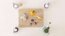 A platter of felt food including strawberries, oranges, and cookies, surrounded with four mugs of tea, all made in Sanae Ishida's Sew Felt Play Food class on Creativebug.
