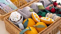 A tray of felt food including strawberries, oranges, and cookies, surrounded with two mugs of tea, all made in Sanae Ishida's Sew Felt Play Food class on Creativebug.