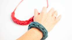 A hand wearing a turquoise finger knit bracelet made in Faith Hale's Finger Knitting class on Creativebug.