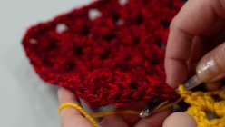 A pair of hands crocheting together two granny squares in Twinkie Chan's Crochet a Granny Square Cardigan class on Creativebug. 