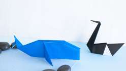 A folded paper origami whale and swan made in Faith Hale's Origami Safari Daily Practice class on Creativebug
