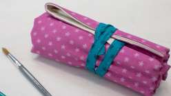 A purple pencil roll full of a rainbow of colored pencils, made in Faith Hale's Sew a Paint Brush and Pencil Roll class on Creativebug.