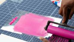 Sarah Matthews rolling paint onto a hand-carved lino block in her Make a Block Printed Notepad class on Creativebug.